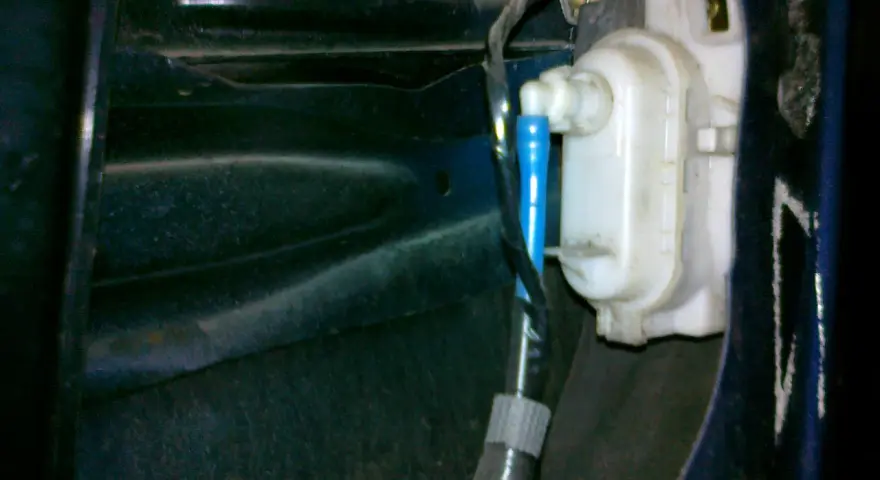 Mechanizm zamka w drzwiach VW Polo. Widoczny siłownik i przewody, pomocne przy pytaniu jak zamontować centralny zamek VW Polo.