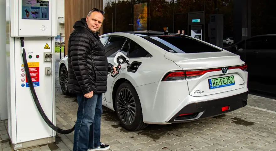 Mężczyzna tankuje białą Toyotę Mirai na jednej z pierwszych stacji wodorowych w Polsce.