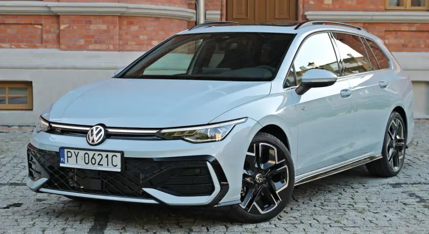 Jasny VW Golf 8 Variant na brukowanej ulicy przed ceglanym budynkiem. Elegancki kombi z nowoczesnym designem.