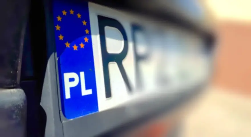 Zbliżenie na polską tablicę rejestracyjną z symbolem UE. Litery "PL" i fragment numeru rejestracyjnego są wyraźne.