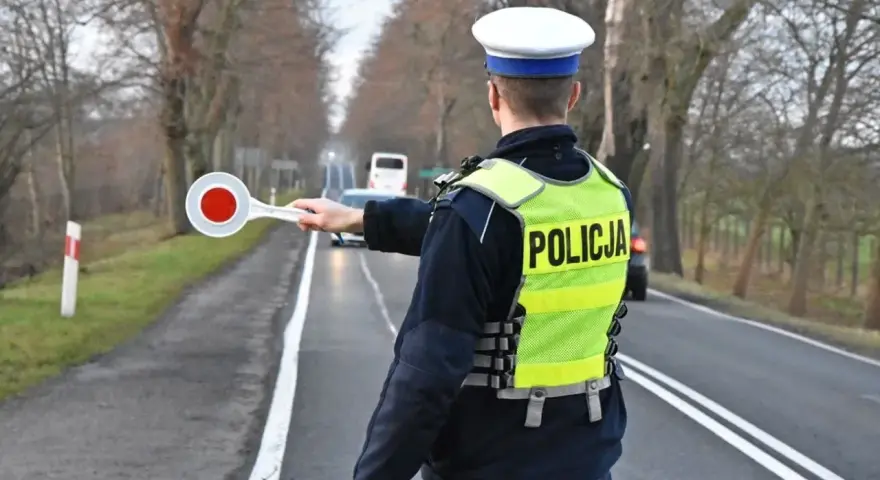 Policjant w kamizelce odblaskowej zatrzymuje ruch, by sprawdzić, ile promili ma kierowca.