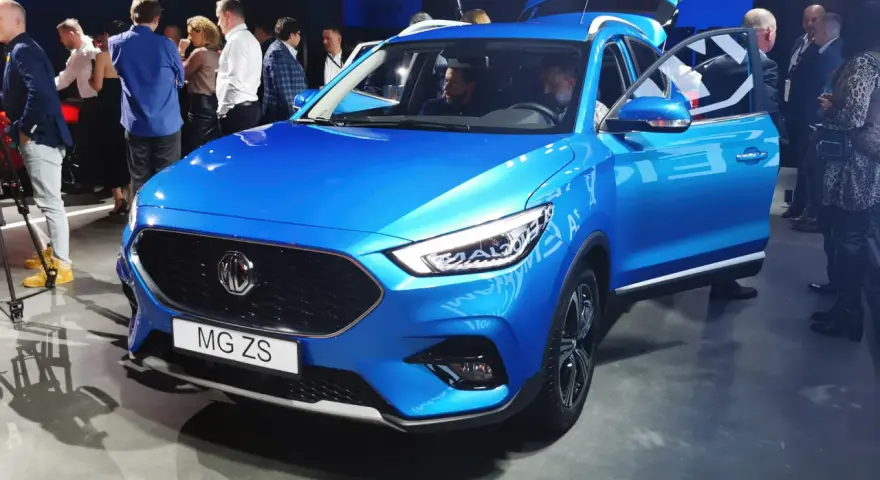 Błękitny MG ZS na prezentacji. Ludzie oglądają nowy model marki MG.