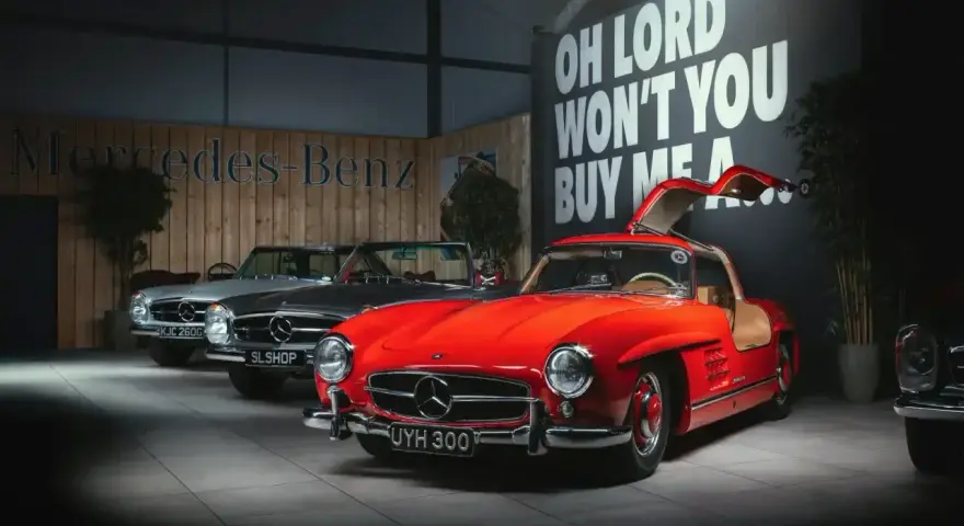 Czerwony Mercedes 300 z drzwiami skrzydłowymi, obok srebrny i szary model.