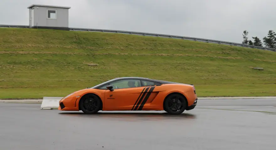 Pomarańczowe Lamborghini na torze. Zastanawiasz się, ile kosztuje przejazd takim autem?