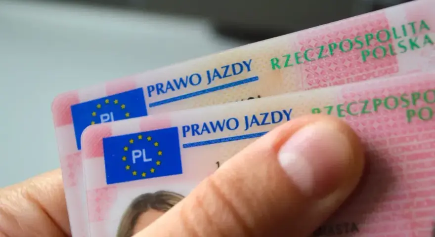 Dłoń trzyma polskie prawa jazdy. Widoczne napisy "PRAWO JAZDY" i "RZECZPOSPOLITA POLSKA" sugerują różne kategorie prawa jazdy.