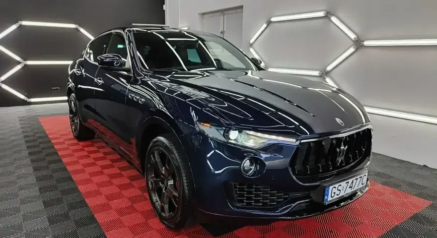 Lśniący, granatowy Maserati Levante na czerwono-czarnej podłodze. Sprawdź aktualną maserati levante cena i poczuj luksus.