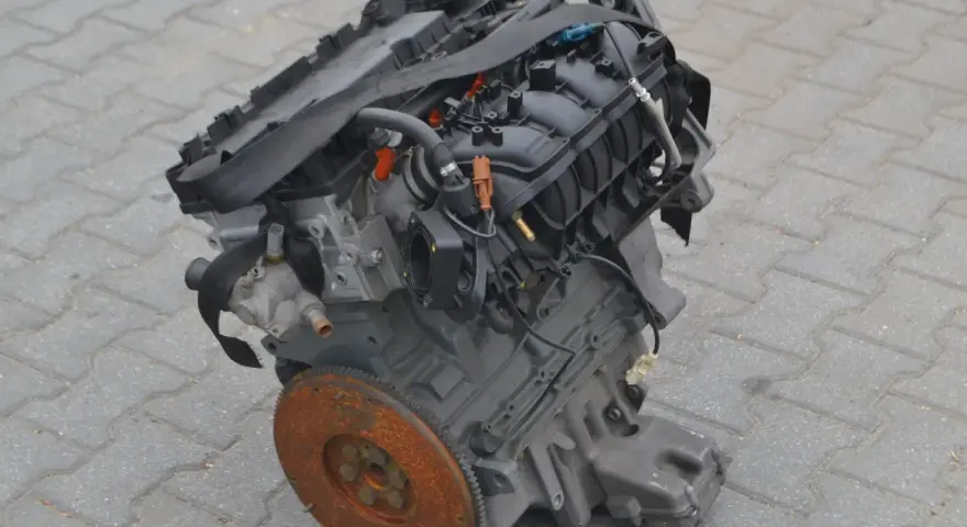 Silnik Alfa Romeo 156, gotowy do montażu. Widoczny koło zamachowe i elementy układu dolotowego.
