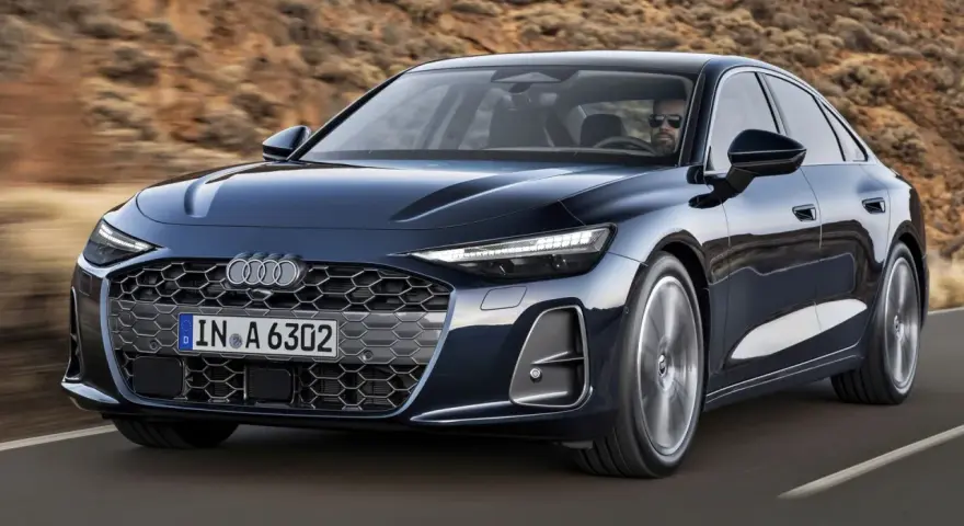 Elegancki, ciemnogranatowy Audi A6 sunie po drodze, z kierowcą w okularach za kierownicą.
