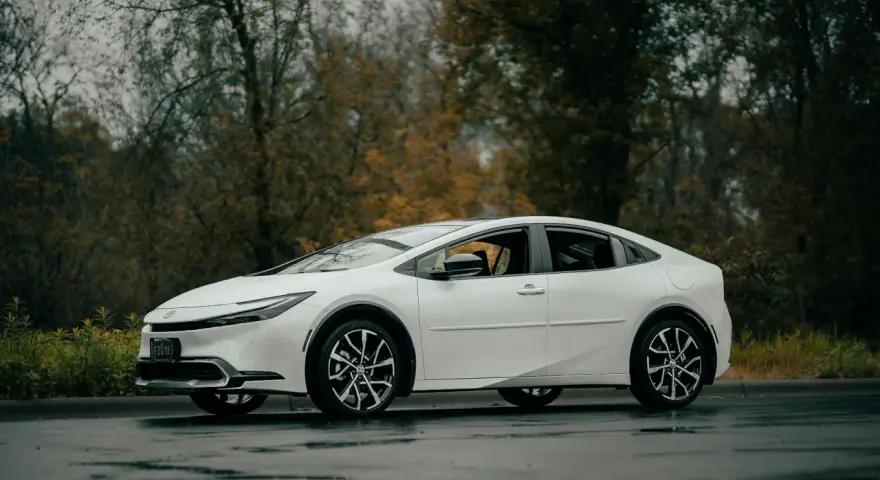 Biała Toyota Prius na mokrej drodze. Zastanawiasz się, ile wytrzymuje bateria w hybrydzie Toyoty?