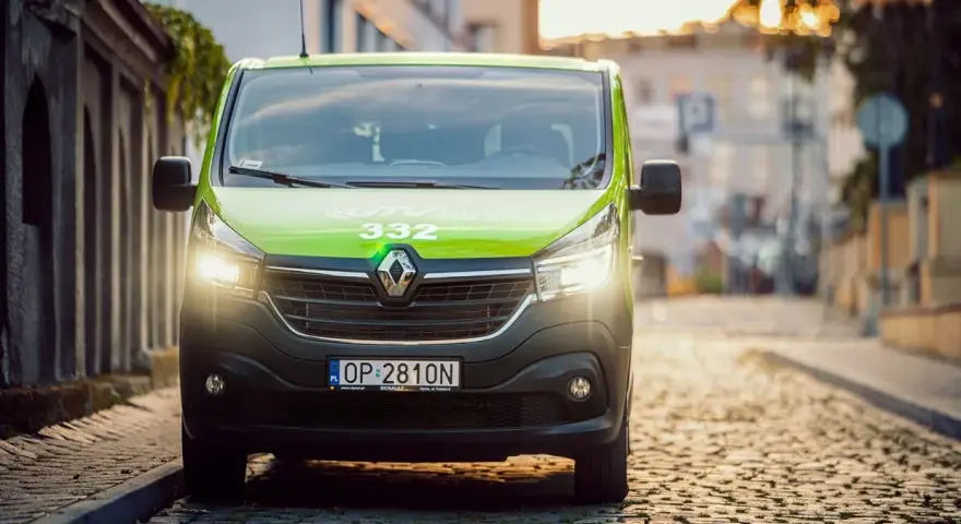 Zielony bus GTV BUS 332 na brukowanej ulicy. Sprawdź, ile kosztuje bus z adresu pod adres.