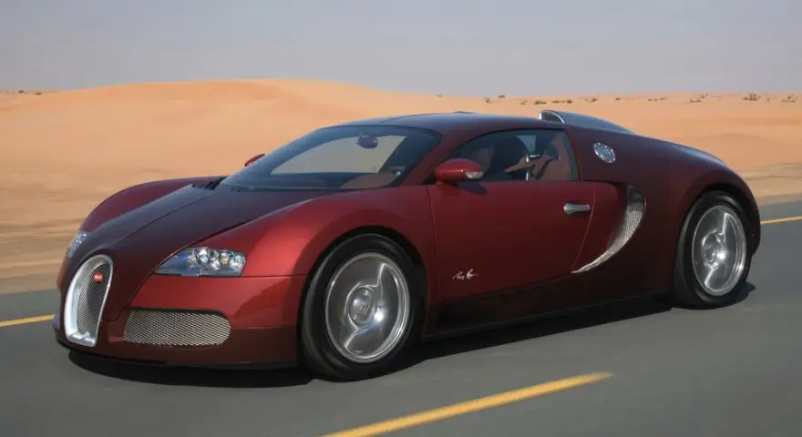 Czerwone Bugatti Veyron sunie po pustynnej drodze. Zastanawiasz się, ile kosztuje taki luksus?