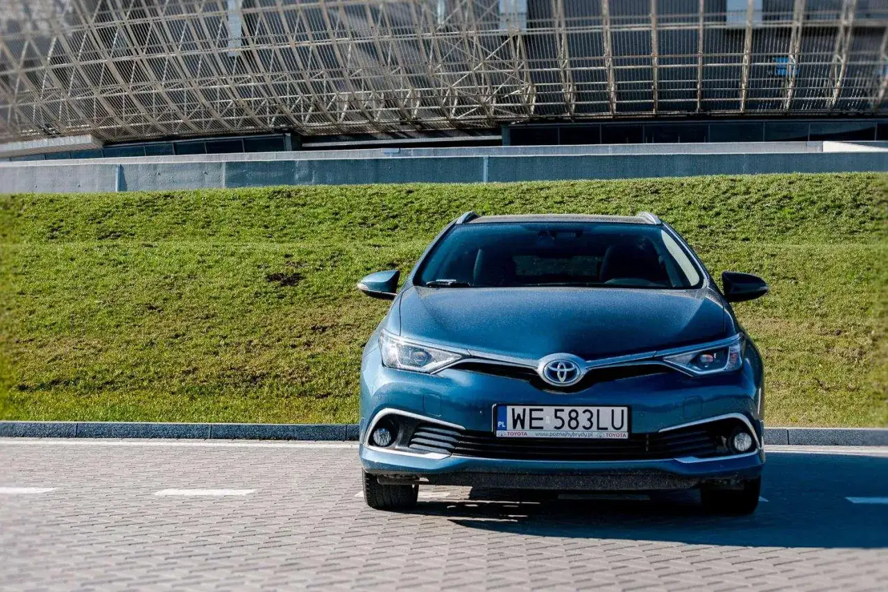 Niebieska Toyota Auris Hybrid zaparkowana przed nowoczesnym budynkiem. Zastanawiasz się, ile pali Toyota Auris Hybrid?