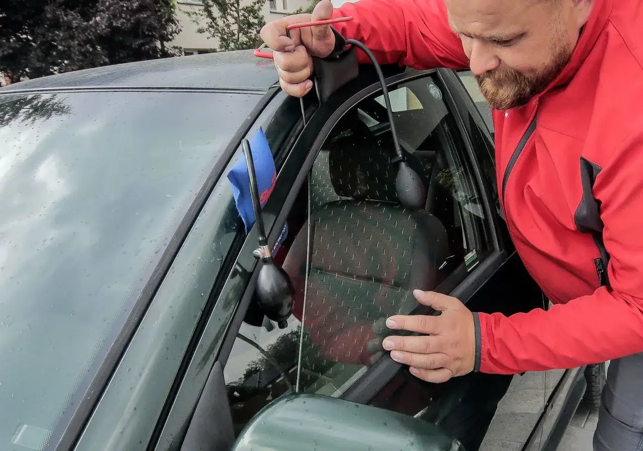 Mężczyzna używa narzędzi do otwarcia samochodu z centralnym zamkiem, gdy kluczyki są w środku.