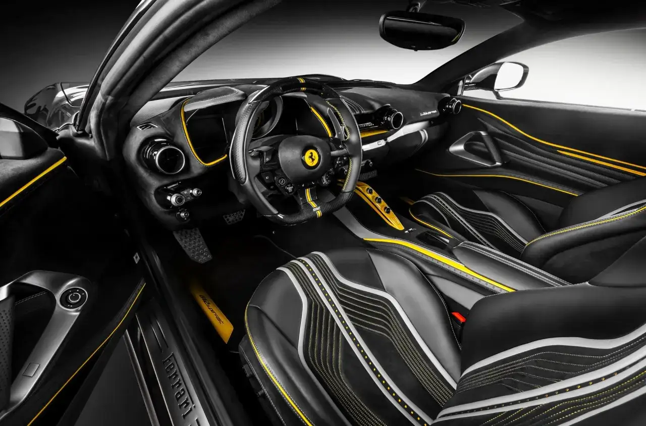 Wnętrze Ferrari w czerni i żółci, z wyścigowymi fotelami i kierownicą. Tak wygląda ferrari z bliska.