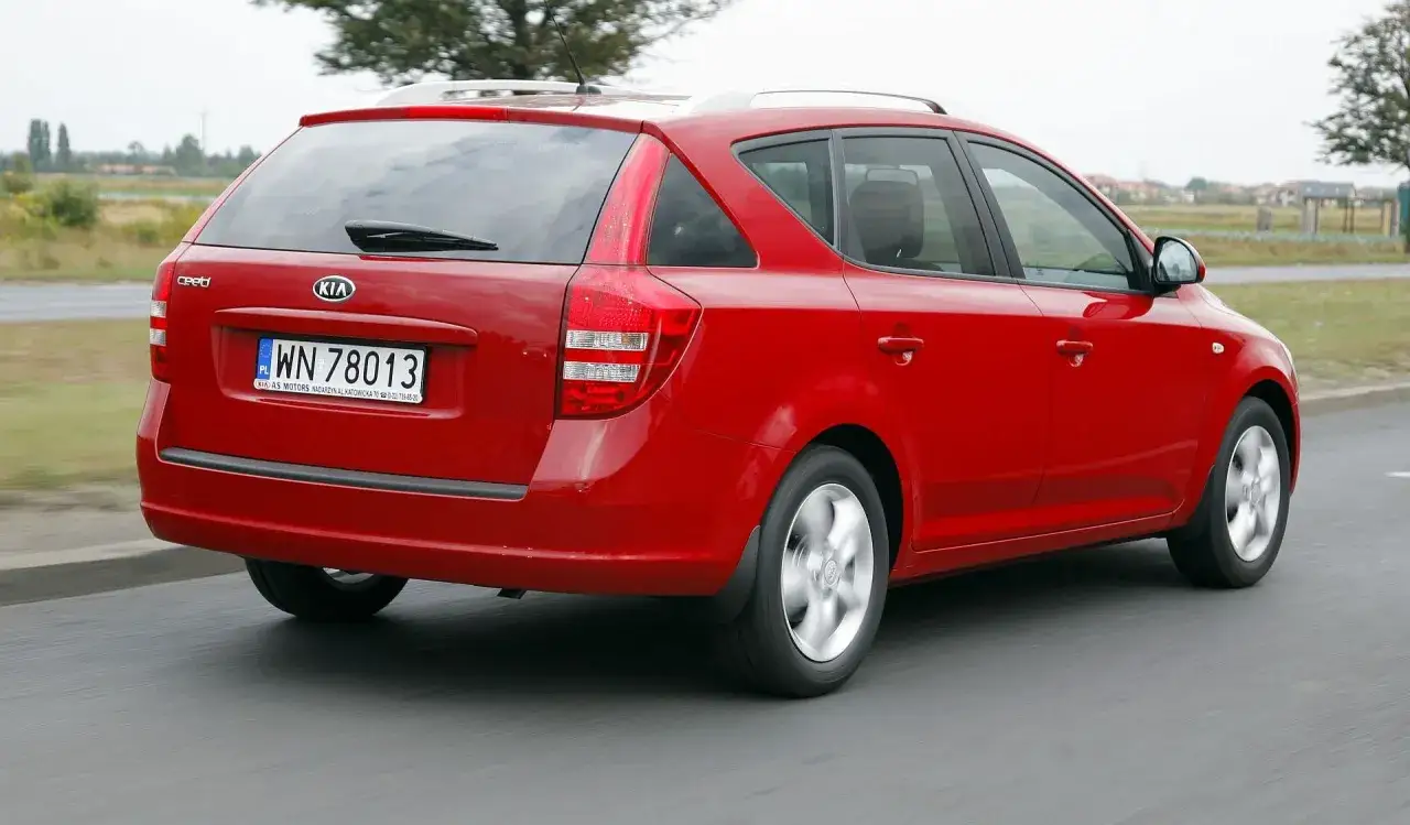 Czerwone kombi Kia Ceed 1. z tablicą rejestracyjną WN 78013 jedzie po drodze.