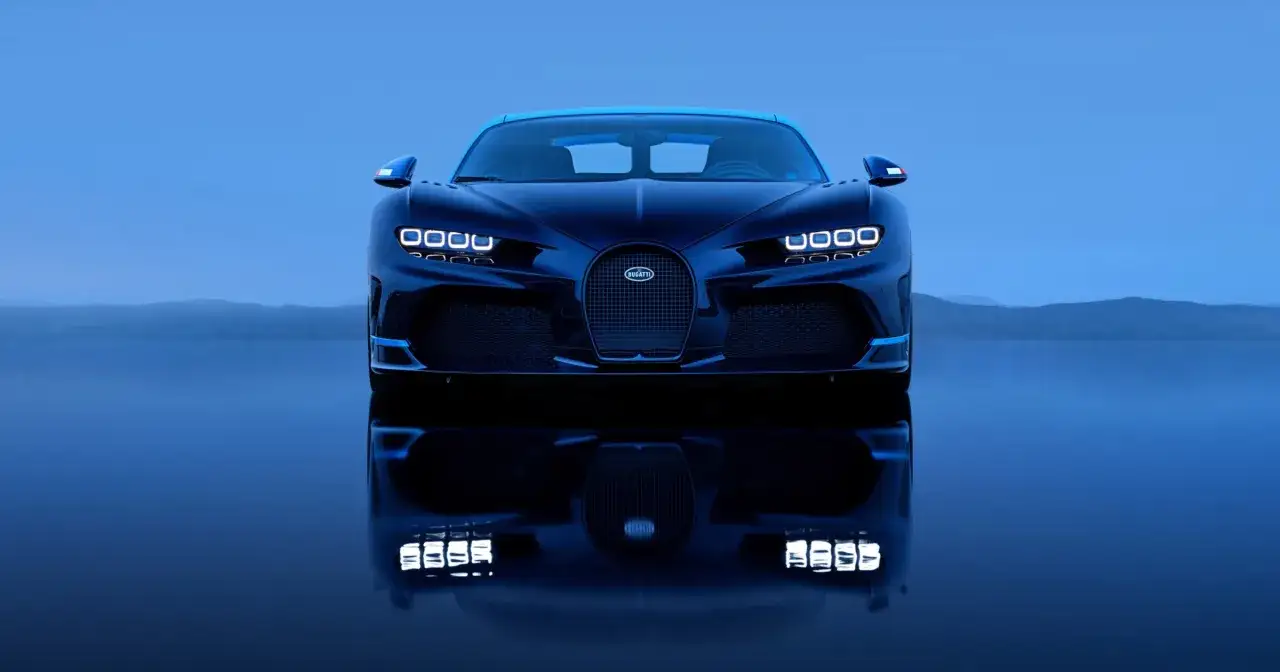 Ciemnoniebieski Bugatti Chiron na tle błękitnego nieba i gór. Kto ma w Polsce taki samochód?