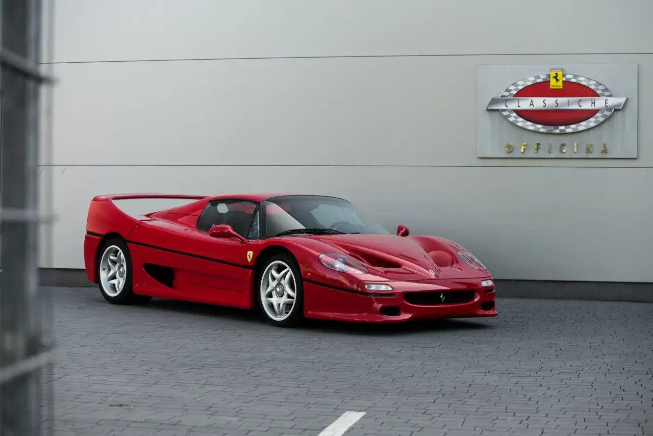 Czerwone Ferrari F50 przed budynkiem z logo
