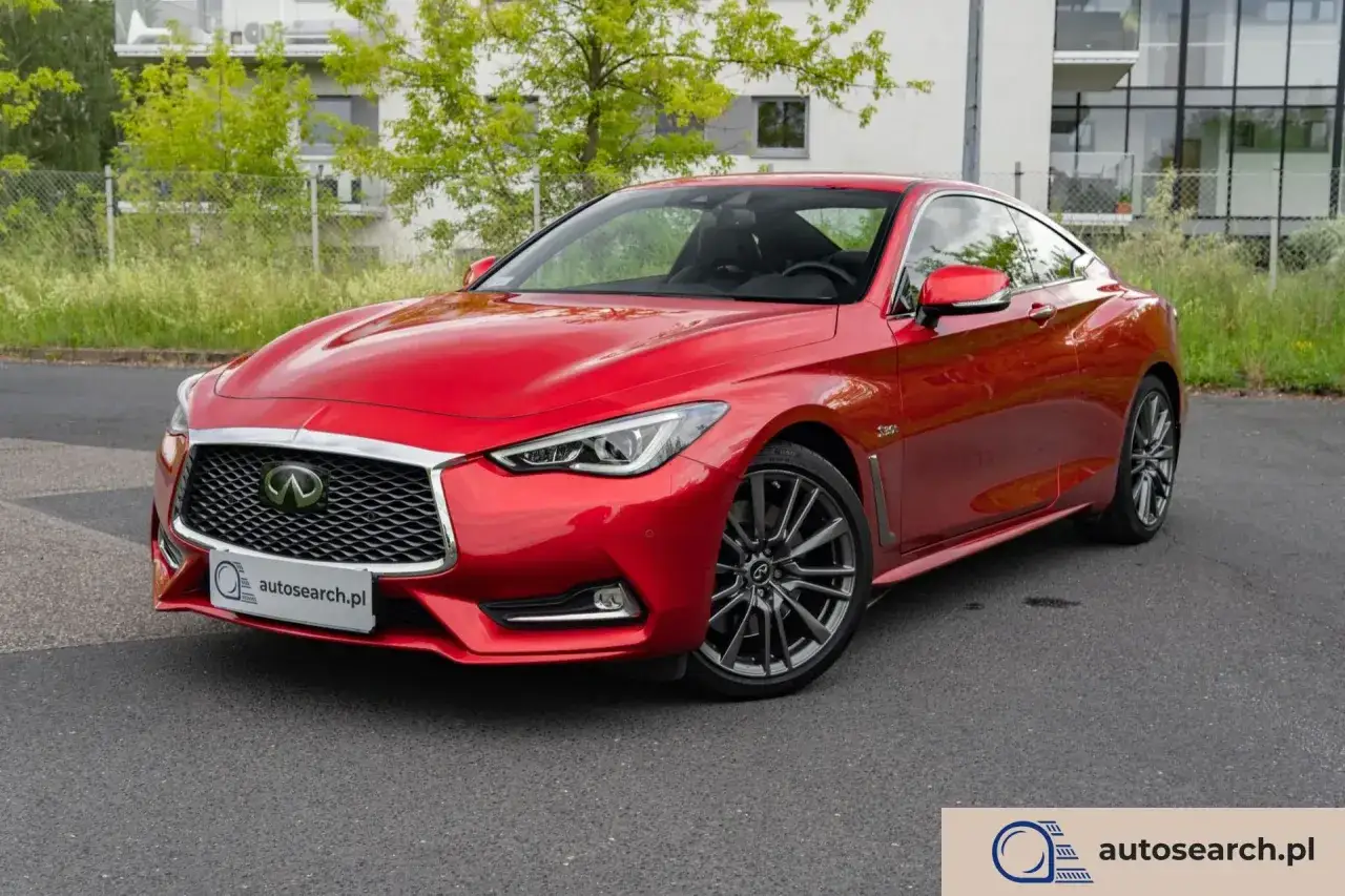 Błyszczący, czerwony infiniti samochód sportowy stoi na drodze przed nowoczesnym budynkiem.