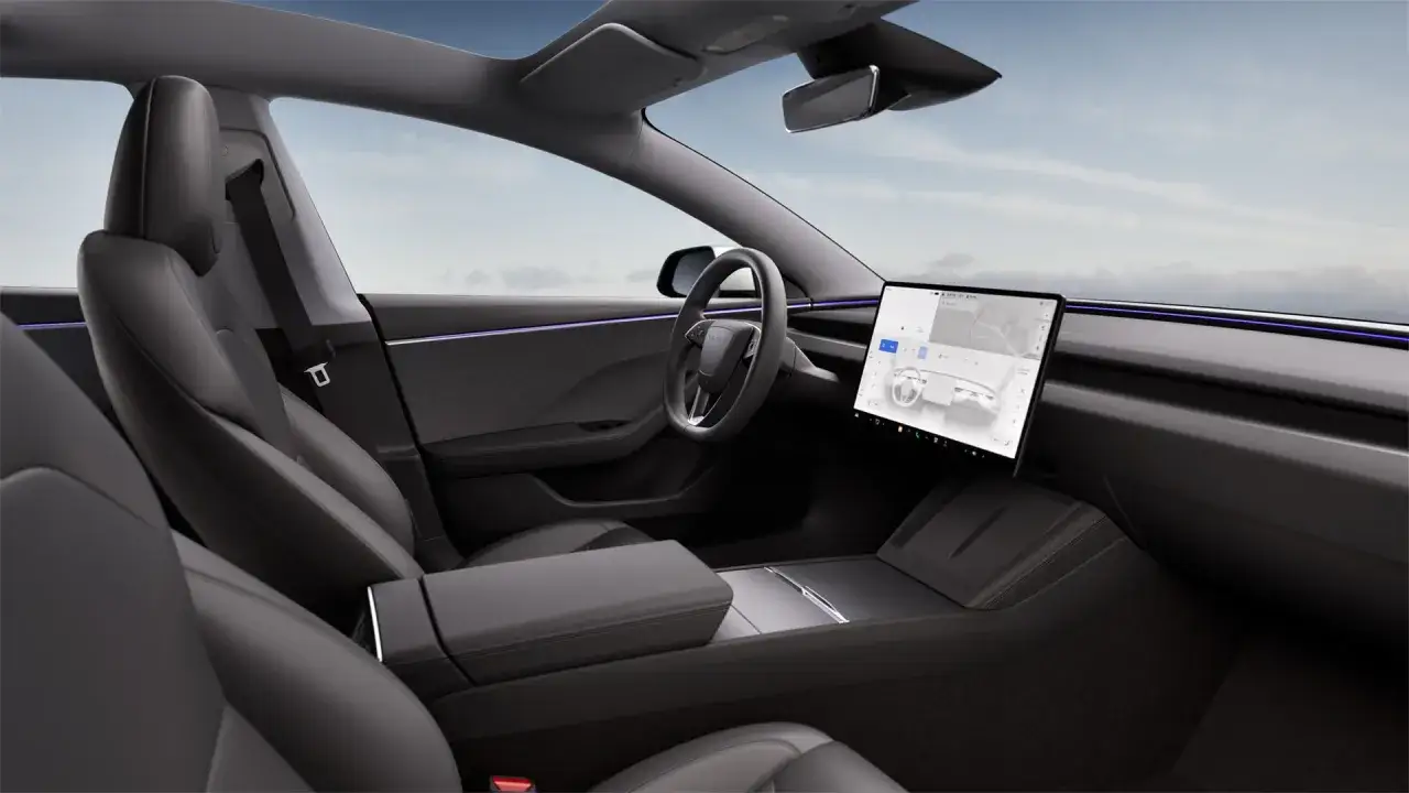 Wnętrze Tesli Model 3. Ciemne, sk&oacute;rzane fotele i minimalistyczna deska rozdzielcza z dużym ekranem. Zastanawiasz się, ile koni ma ten model?