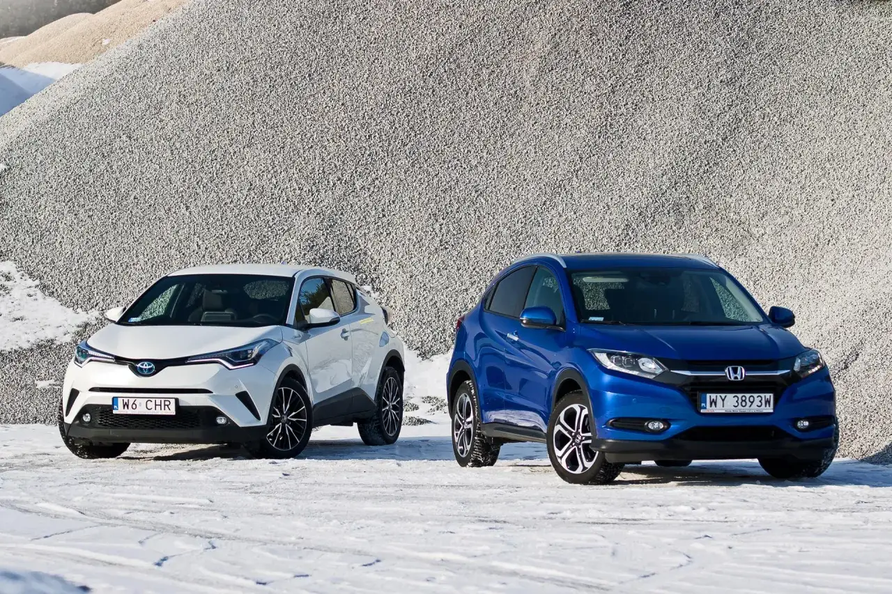 Biała Toyota C-HR i niebieska Honda HR-V stoją obok siebie na śniegu. Która hybryda Honda czy Toyota lepsza?