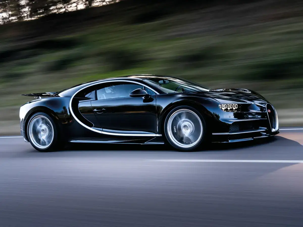 Czarne Bugatti Chiron pędzi po drodze. Zastanawiasz się, ile jest Bugatti w Polsce?
