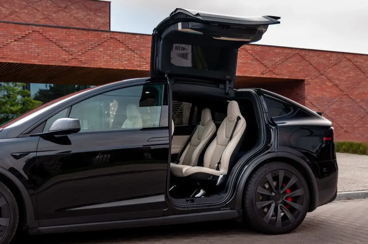 Czarna Tesla Model X z otwartymi drzwiami typu falcon wing i jasnymi skórzanymi fotelami. Zastanawiasz się, ile kosztuje najdroższa Tesla?