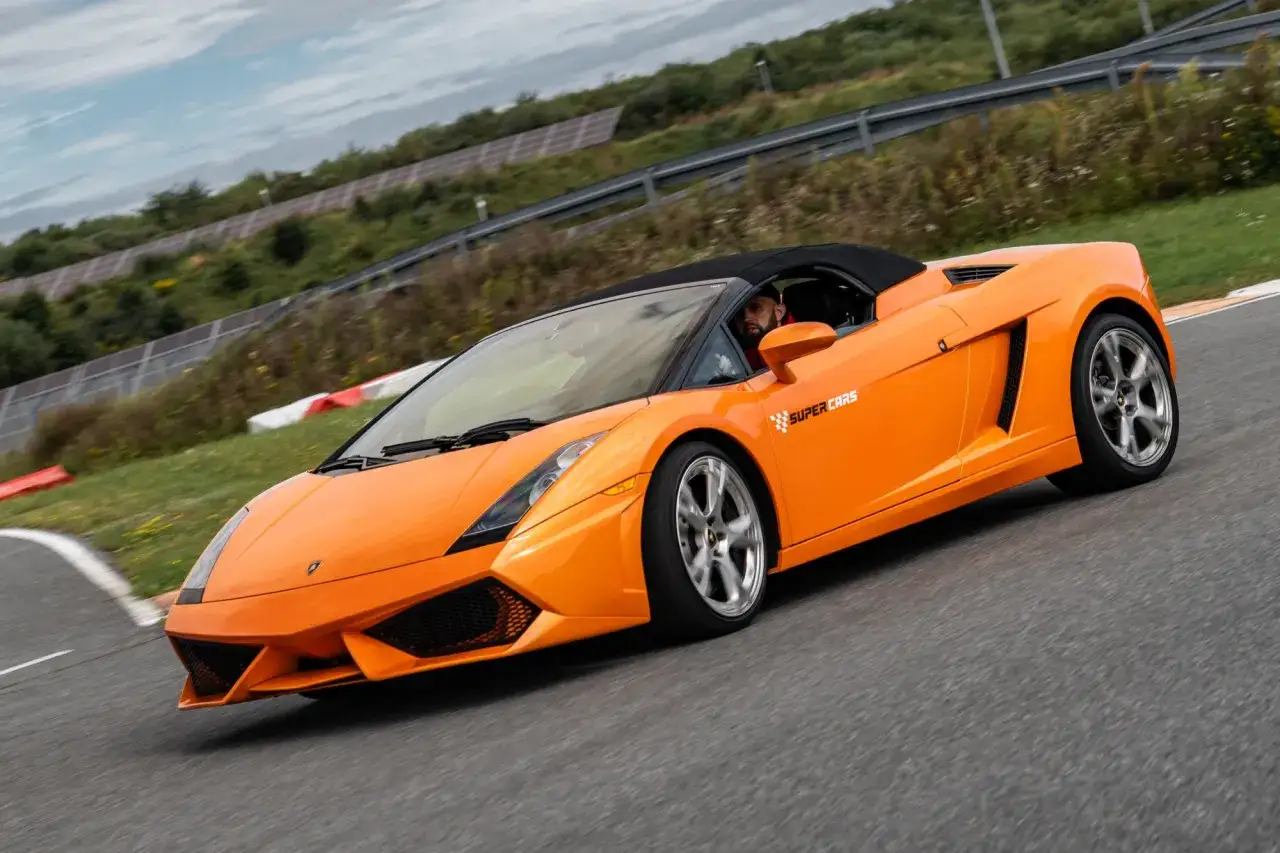 Pomarańczowe Lamborghini Gallardo na torze wyścigowym. Zastanawiasz się, ile kosztuje przejazd takim cackiem?