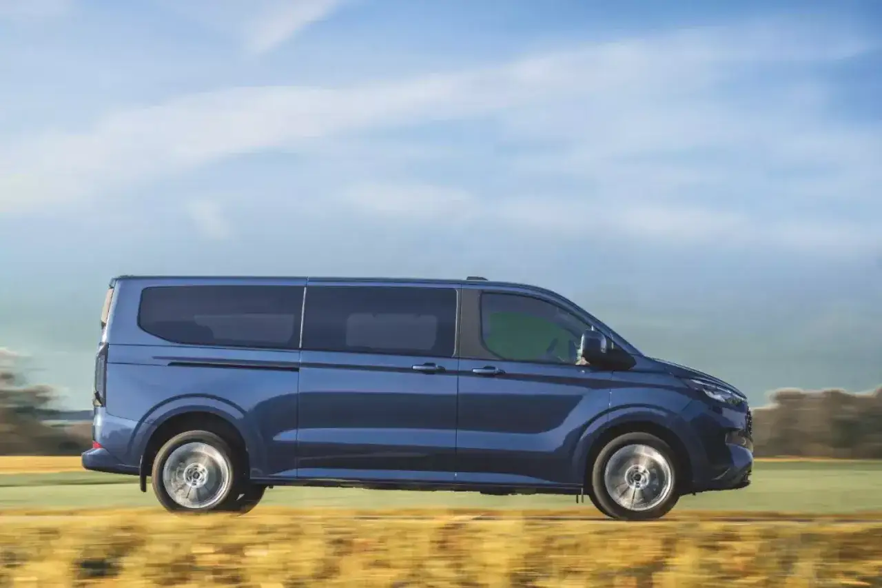 Niebieski bus 9 osobowy w ruchu. Zastanawiasz się, ile pali bus 9 osobowy? Ten model zapewnia komfortową podróż.