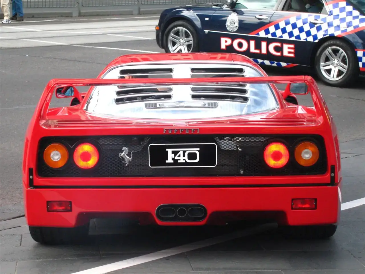 Czerwone Ferrari F40 z charakterystycznym spojlerem i tablicą rejestracyjną 