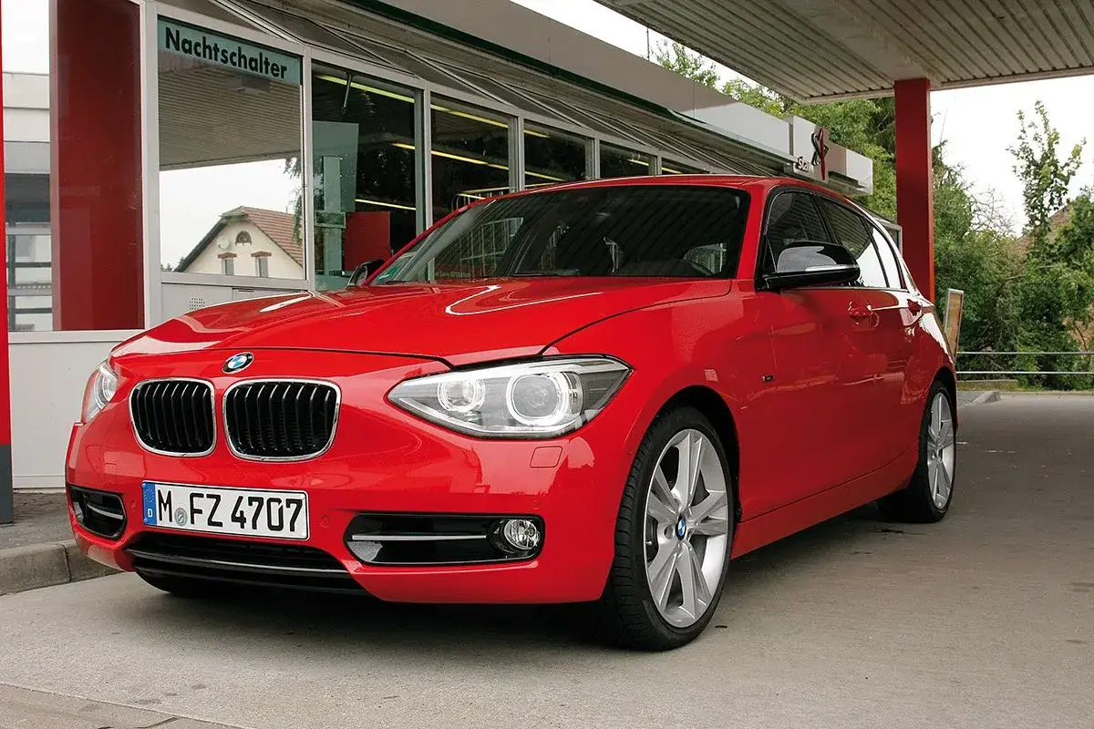 Czerwone BMW e81 z tablicą rejestracyjną M.FZ 4707 stoi pod zadaszeniem.
