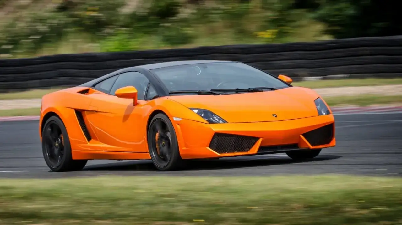 Pomarańczowe Lamborghini pędzi po torze. Zastanawiasz się, ile kosztuje przejazd takim cackiem?