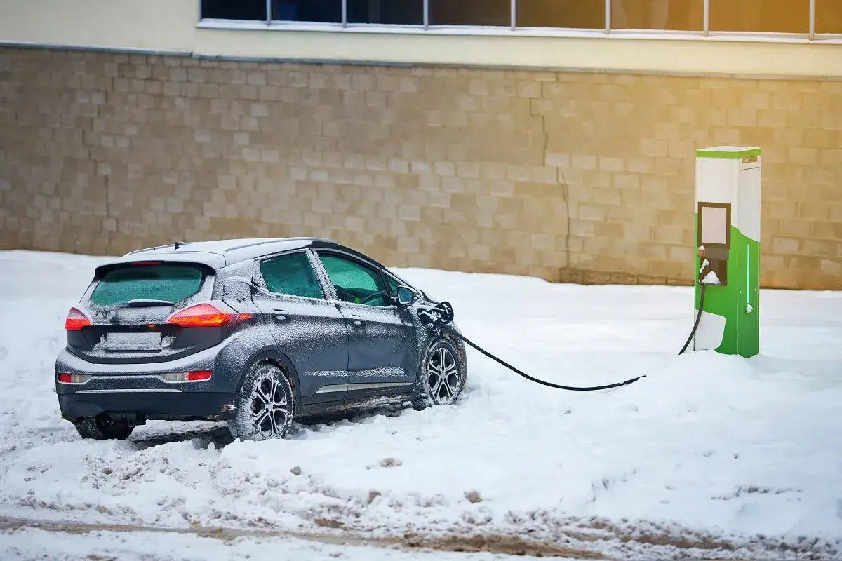 Szary samoch&oacute;d elektryczny ładuje się na śniegu. Zastanawiasz się, ile przejedzie Tesla na jednym ładowaniu w takich warunkach?