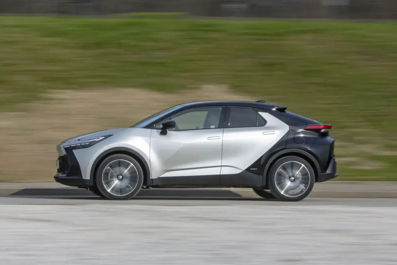 Srebrno-czarna Toyota C-HR Hybrid w ruchu. Zastanawiasz się, ile pali Toyota C-HR Hybrid? Ten stylowy SUV pokonuje kolejne kilometry.