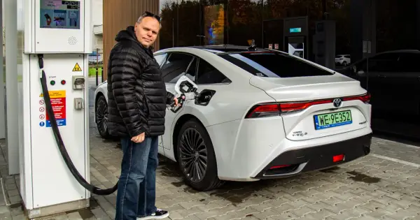 Mężczyzna tankuje białą Toyotę Mirai na jednej z pierwszych stacji wodorowych w Polsce.