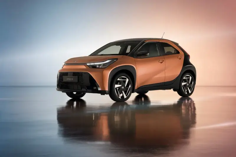 Pomarańczowa Toyota Aygo X z czarnymi dodatkami, idealna do miasta. Sprawdź atrakcyjną toyota hybryda cena.