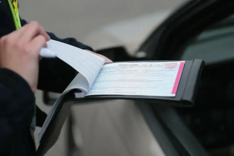Policjant wypisuje mandat za kolizję. Dokument zawiera numer seryjny i pieczęć.