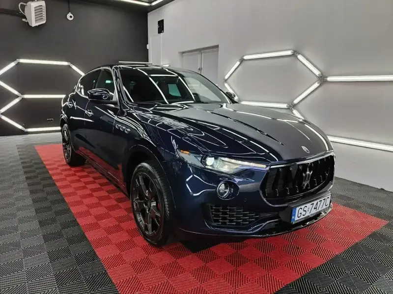Lśniący, granatowy Maserati Levante na czerwono-czarnej podłodze. Sprawdź aktualną maserati levante cena i poczuj luksus.